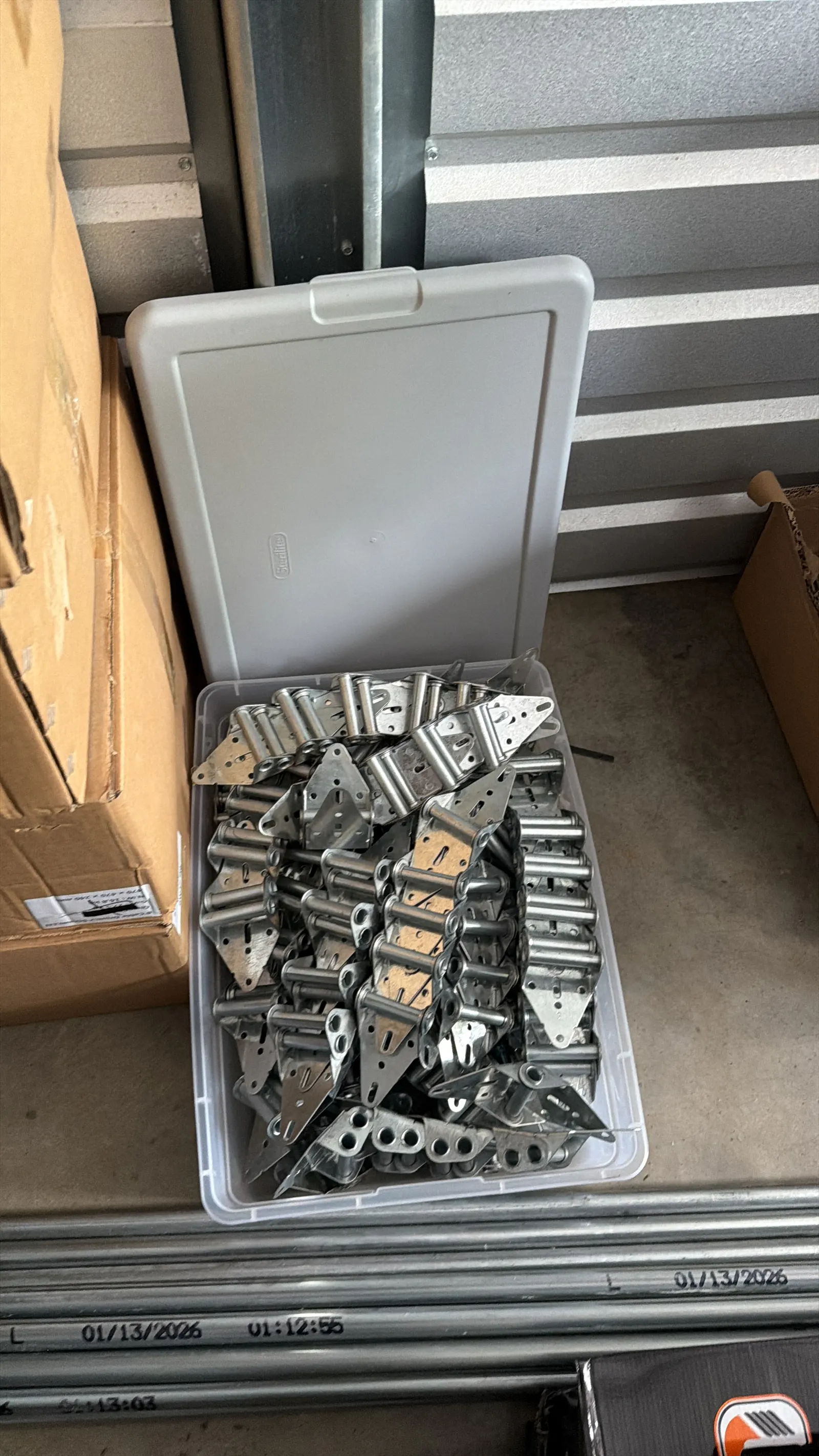 Box of new garage door hinges ready for a repair
