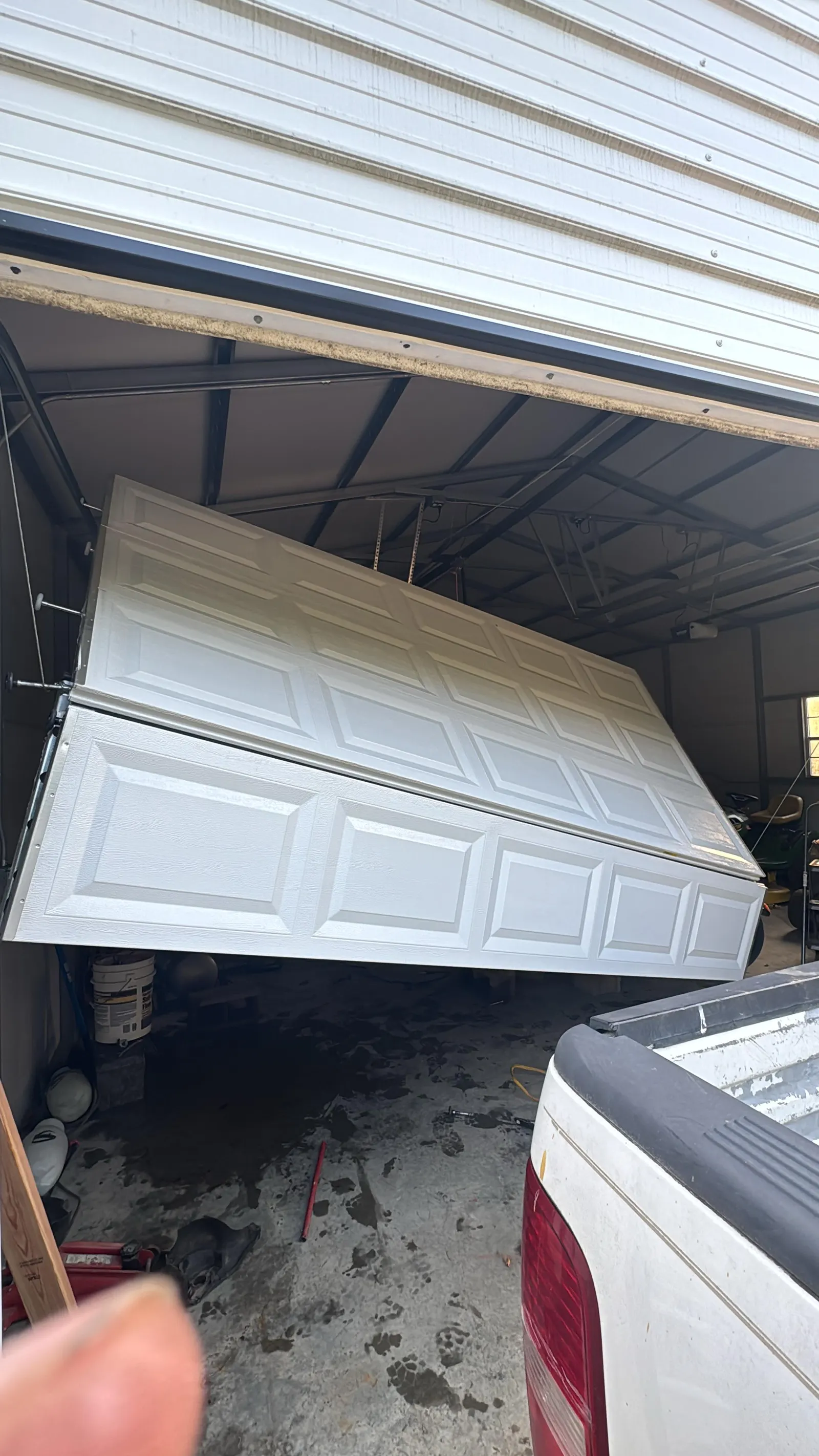 Raised-panel garage door knocked off its tracks and hanging crooked
