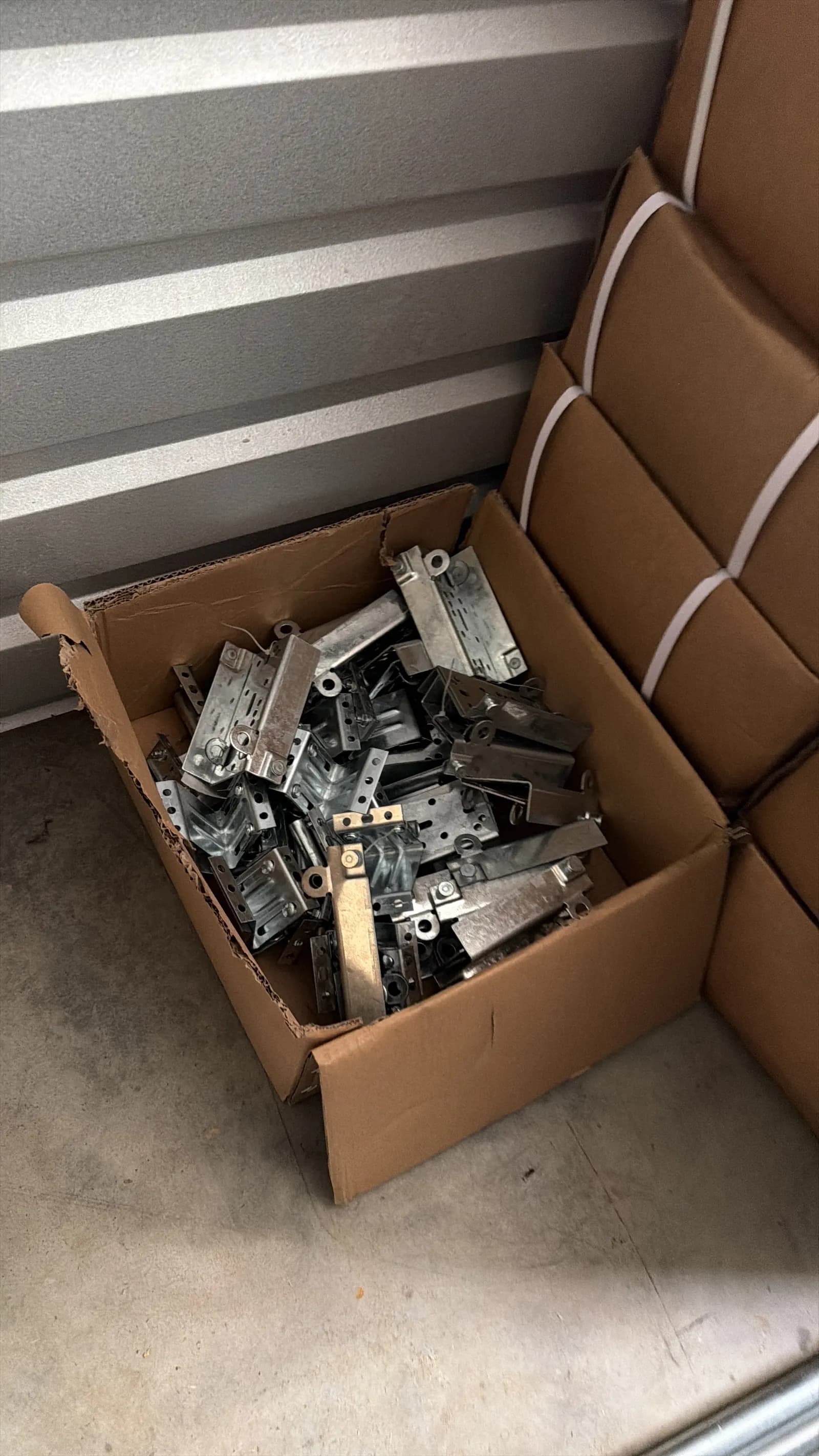 Replacement garage door hinges and brackets in a parts box