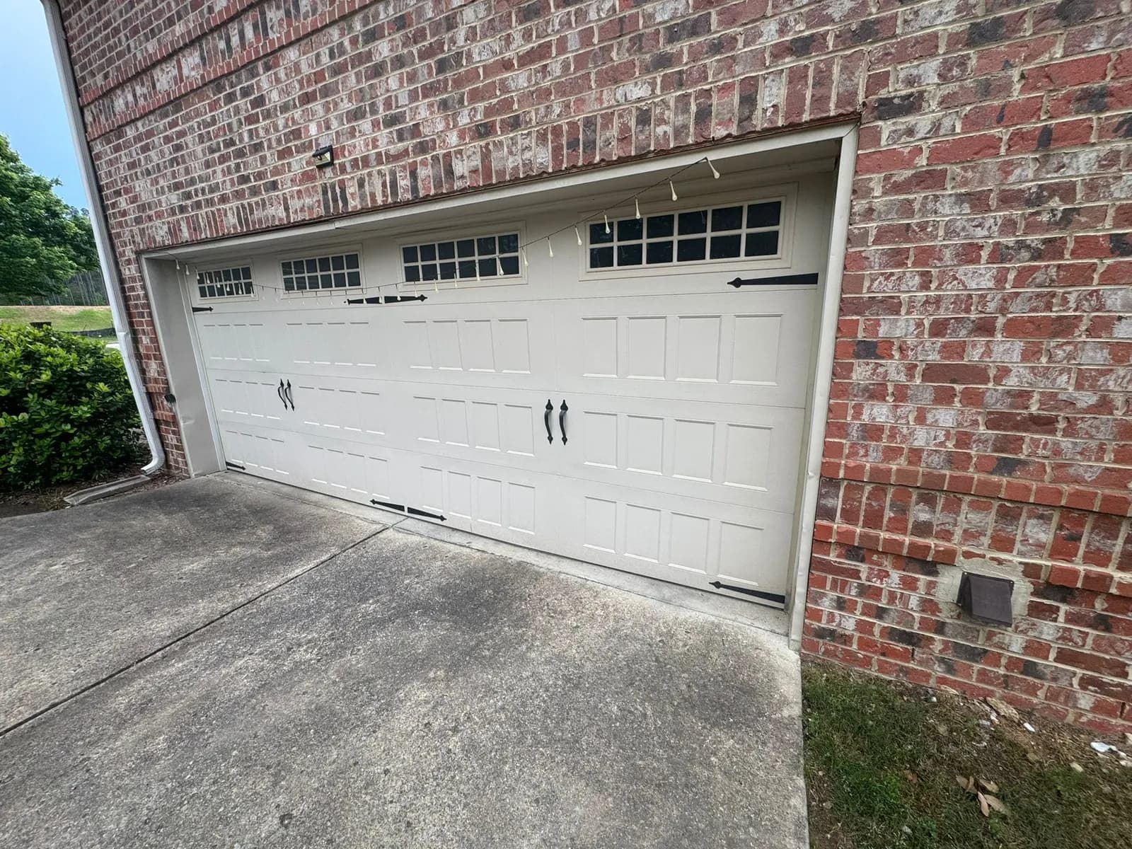 Two-car carriage-style garage door with windows on a brick house