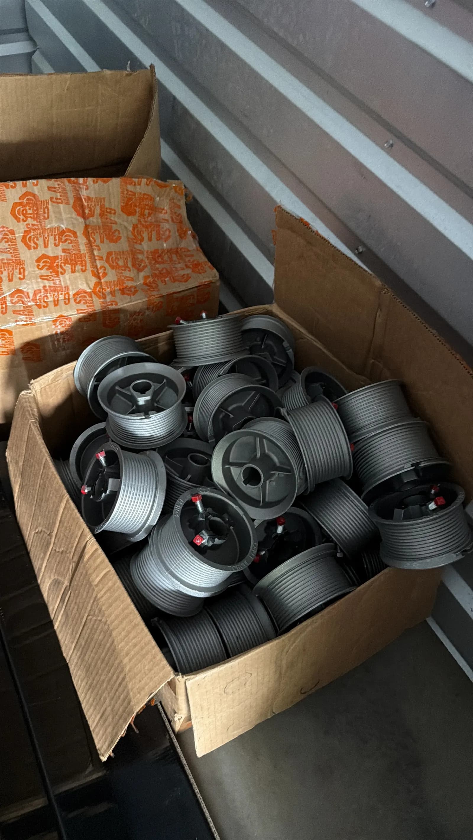 Box of new cable drums for garage door repairs