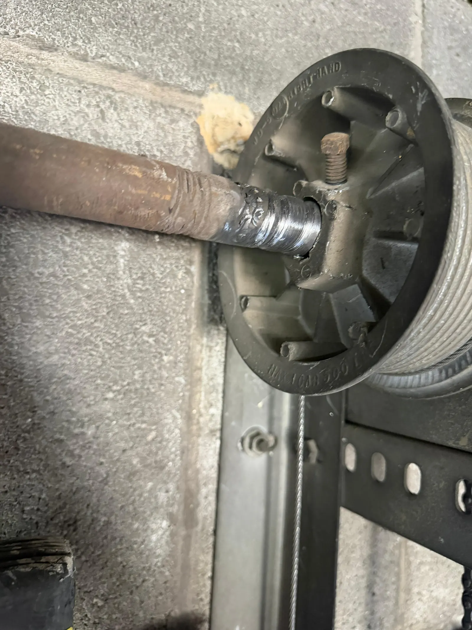 Cable drum on a torsion shaft beside a concrete wall