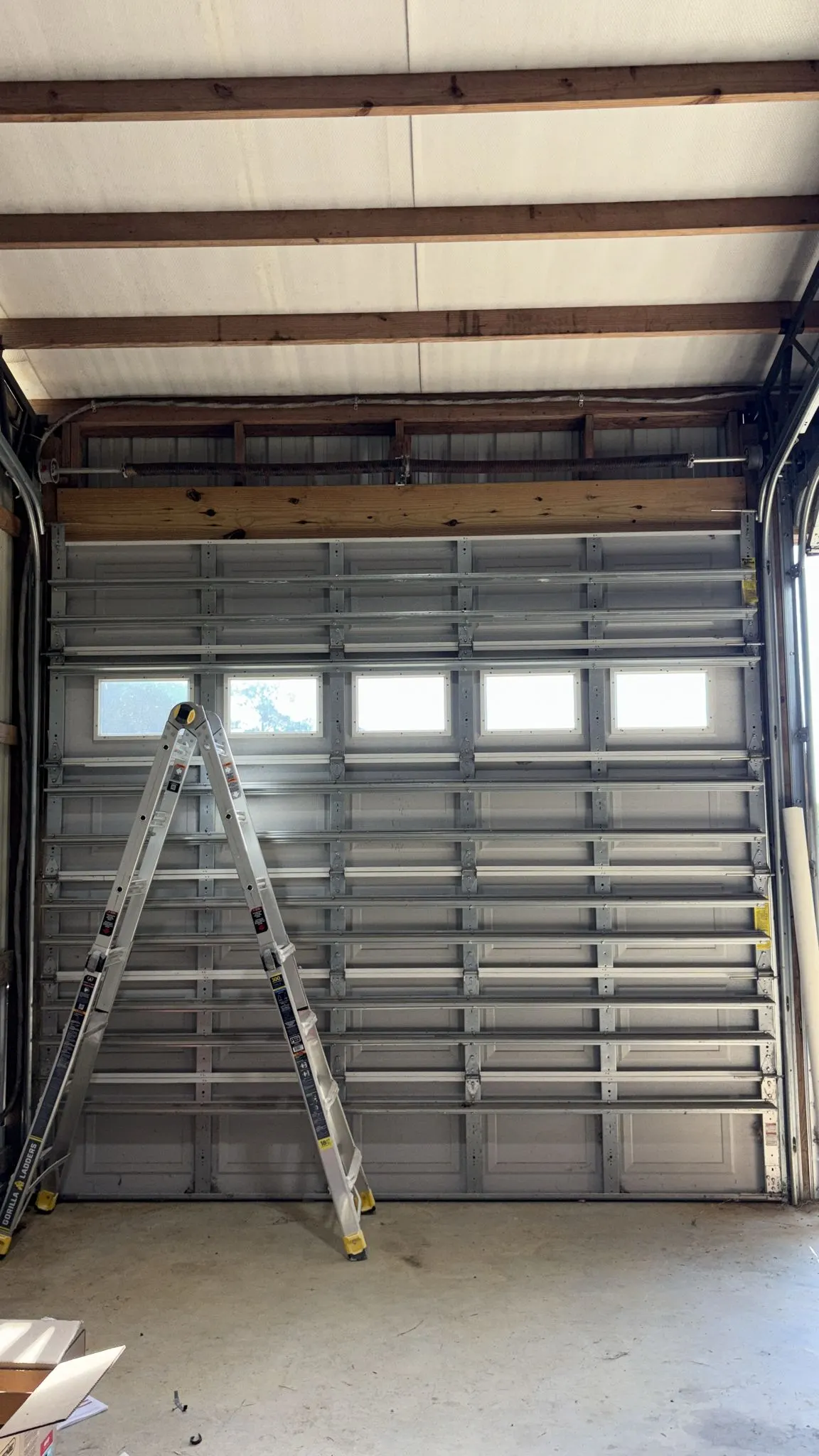 Commercial sectional door with window row, technician ladder below